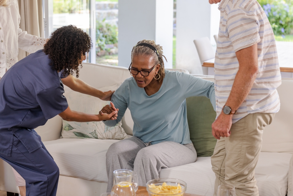Caregiver helps woman in assisted living facility to stand