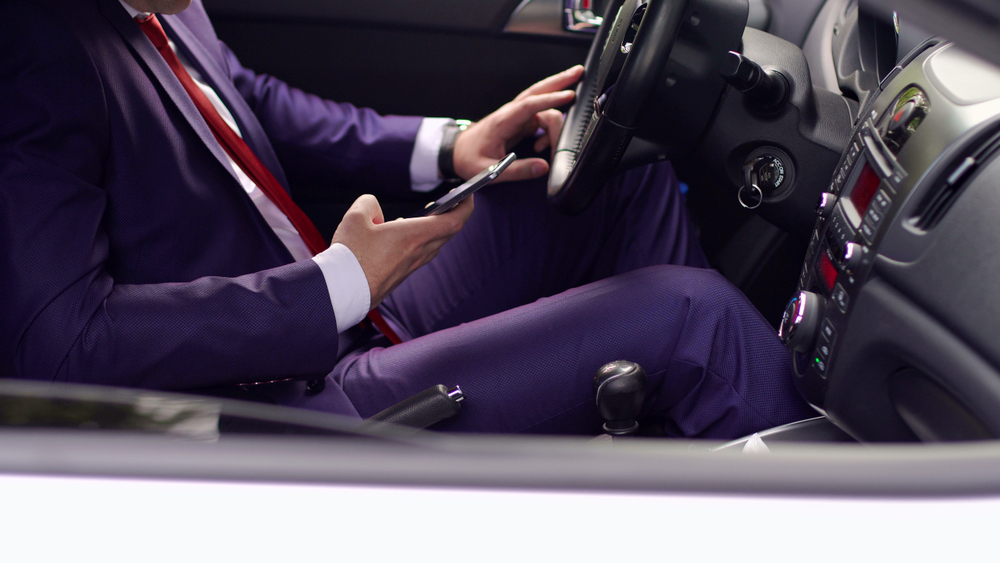 Close-up of a suited driver using a cell phone