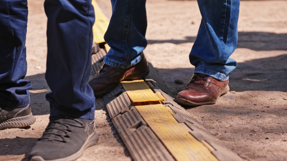 Close-up of feet stepping over a ground cable cover